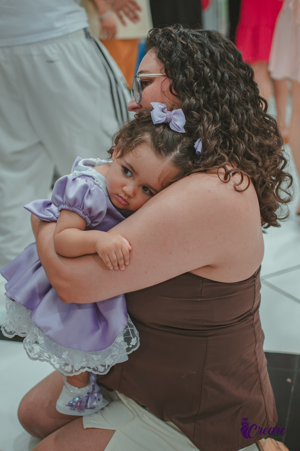 Uma mulher abraçada com sua bebê, duranye festa de aniversário de 1 ano.