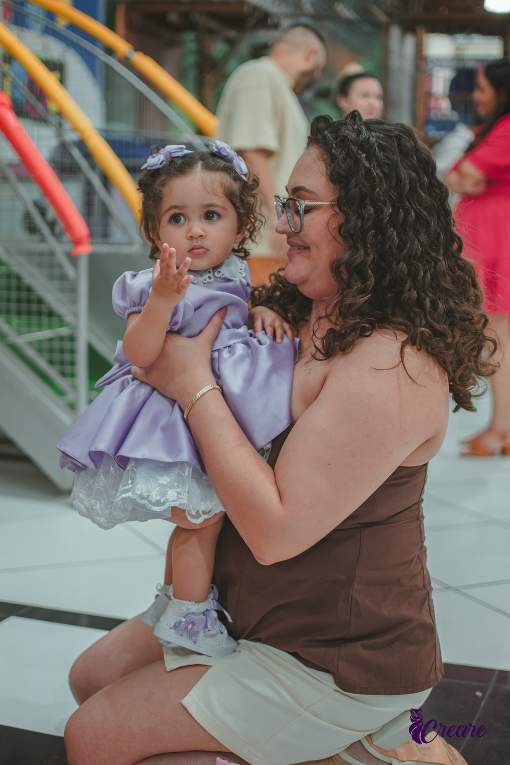 Uma mulher brincando com sua bebê, durante festa de aniversário de 1 ano.