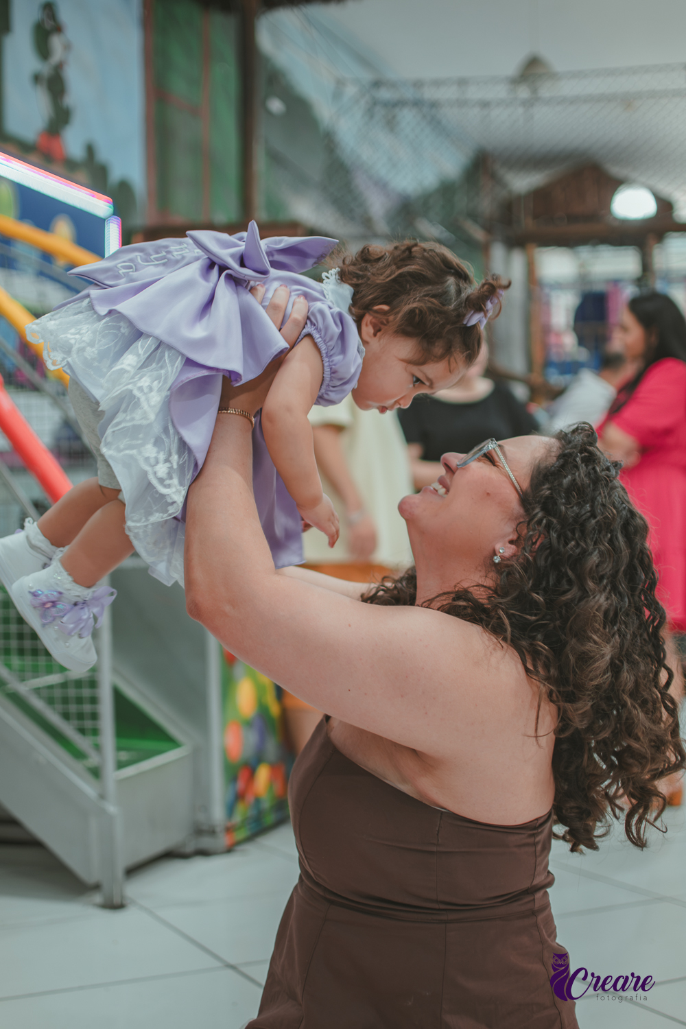 Uma mulher brincando com sua bebê, durante festa de aniversário de 1 ano.