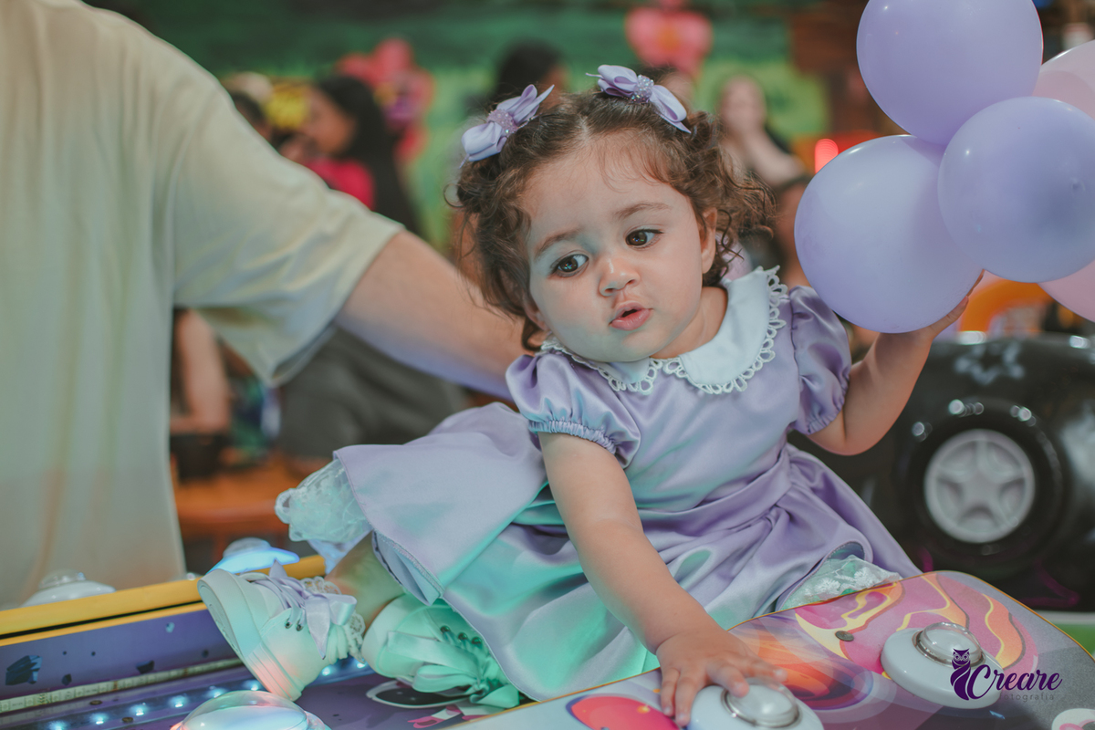Uma bebê brincando durante sua festa de anievrsário de 1 ano.