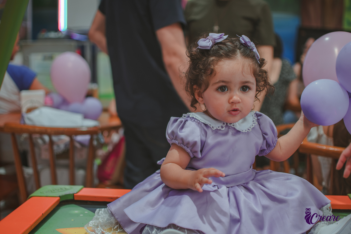 Uma bebê brincando durante sua festa de anievrsário de 1 ano.