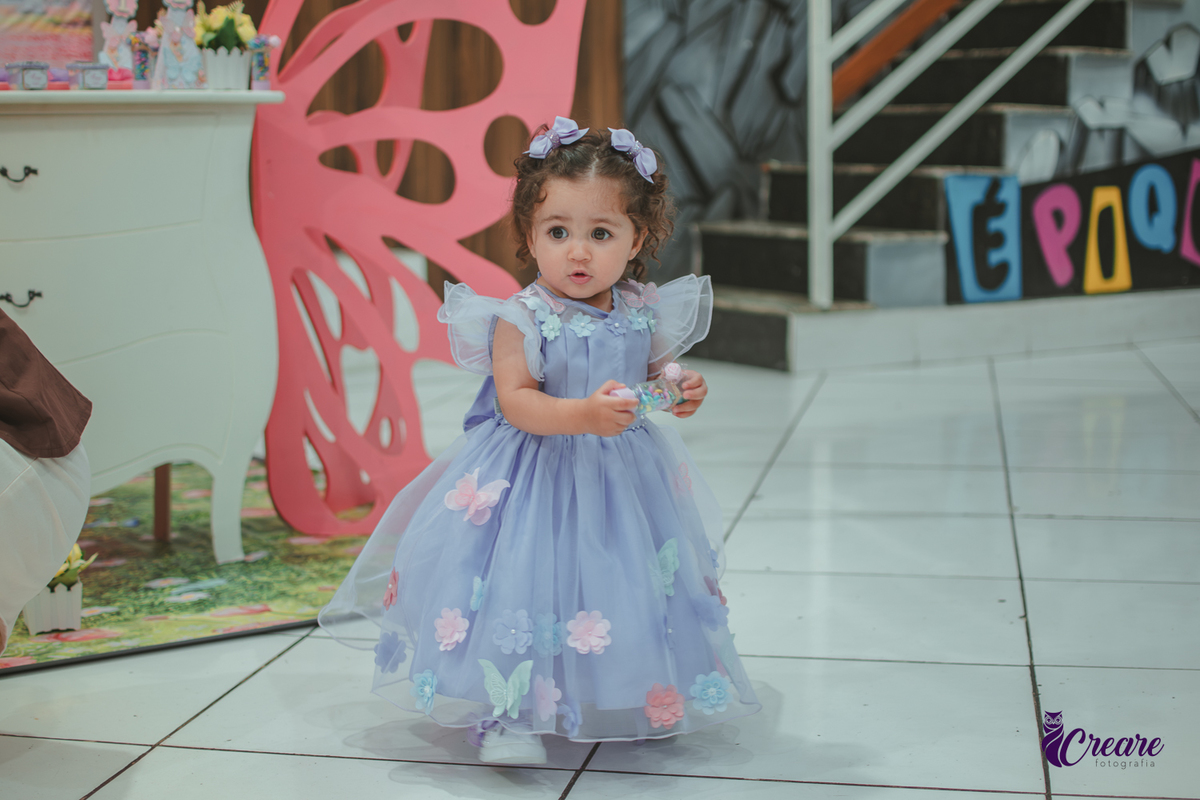 Uma menina usando vestido roxo e andando pelo salão, durante sua festa de aniversário de 1 ano no Buffet É Pique em Mauá.