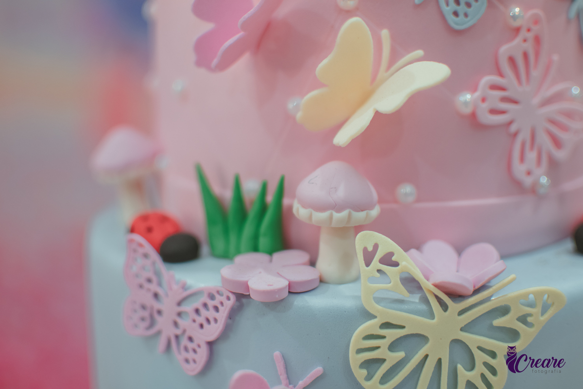 detalhes de um bolo de aniversário de 1 ano, com borboletas flores e cogumelo.