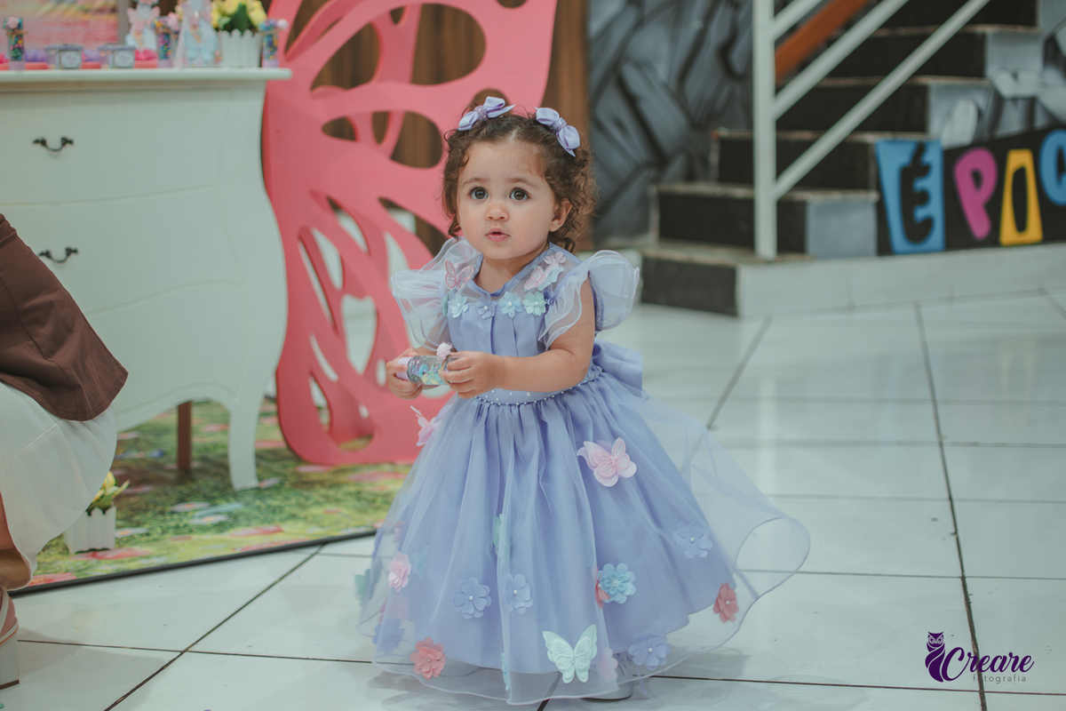 Uma menina usando vestido roxo e andando pelo salão, durante sua festa de aniversário de 1 ano no Buffet É Pique em Mauá.