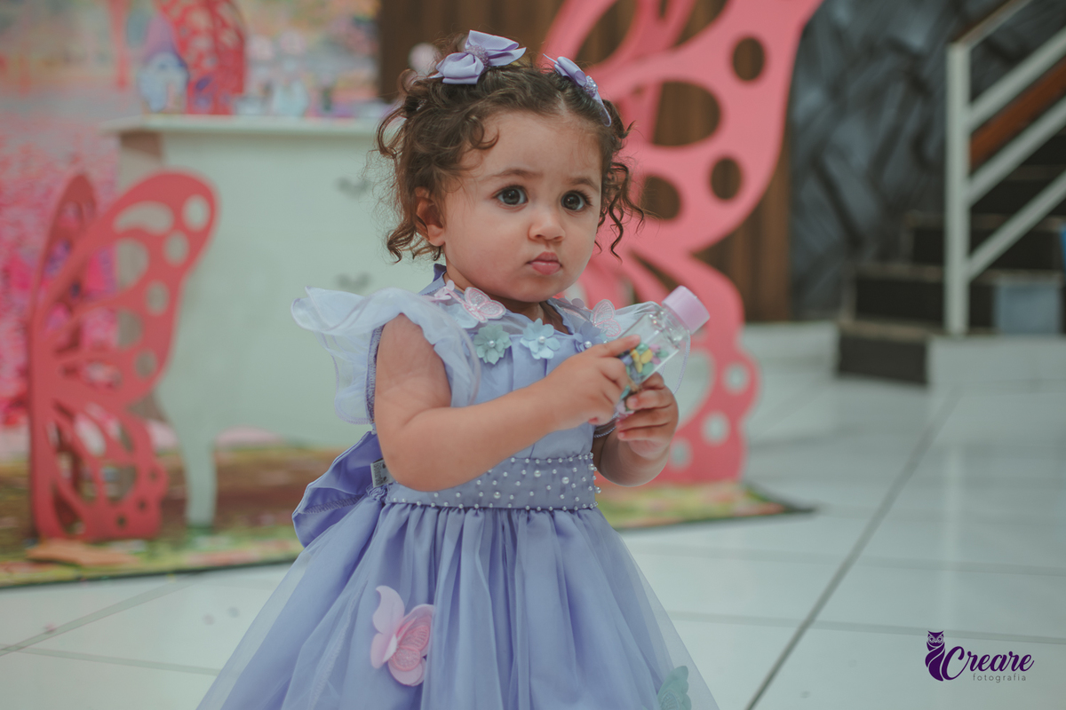 Uma menina usando vestido roxo e andando pelo salão, durante sua festa de aniversário de 1 ano no Buffet É Pique em Mauá.