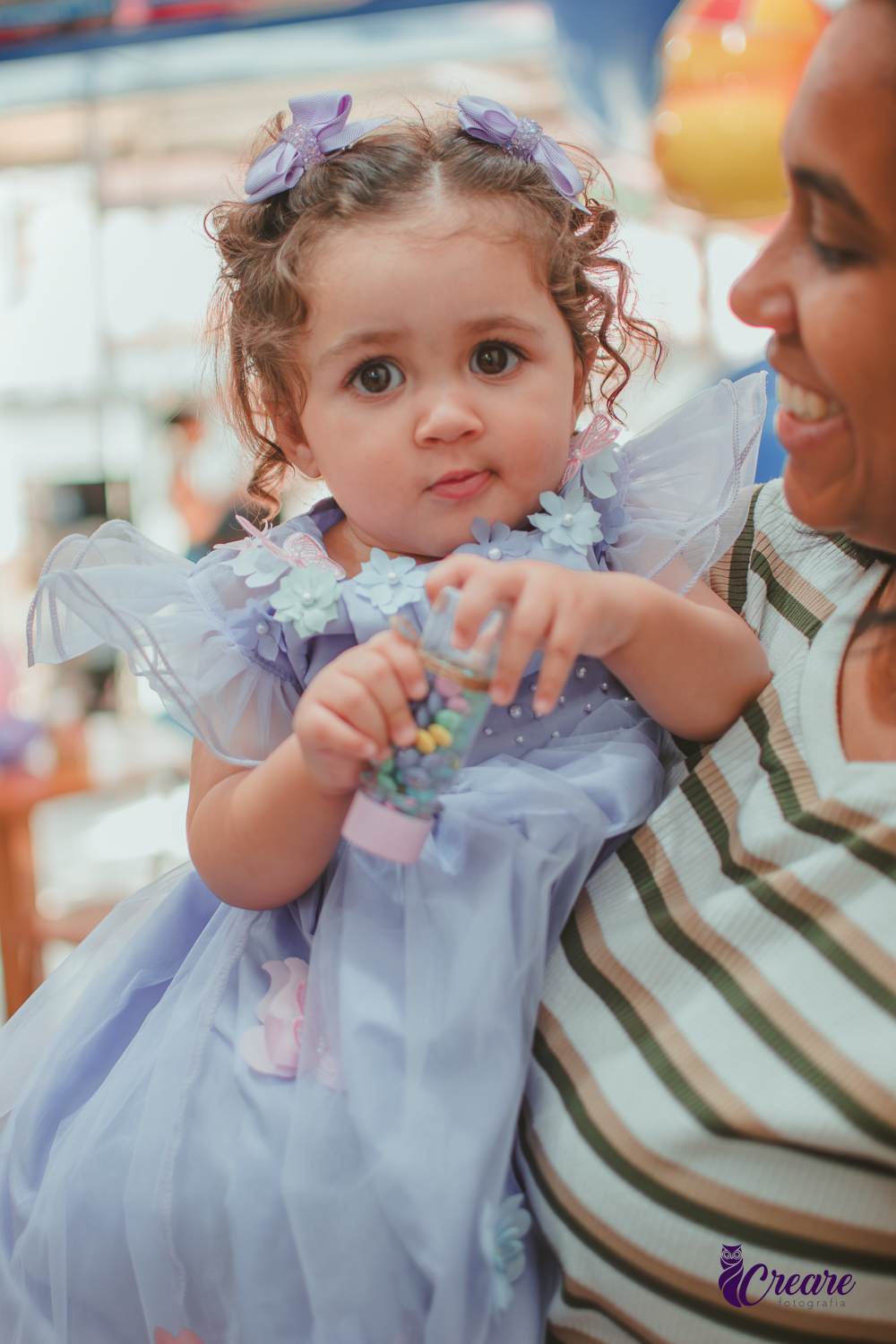 Ume menina segurando um potinho com confetis, durante sua festa de 1 ano.