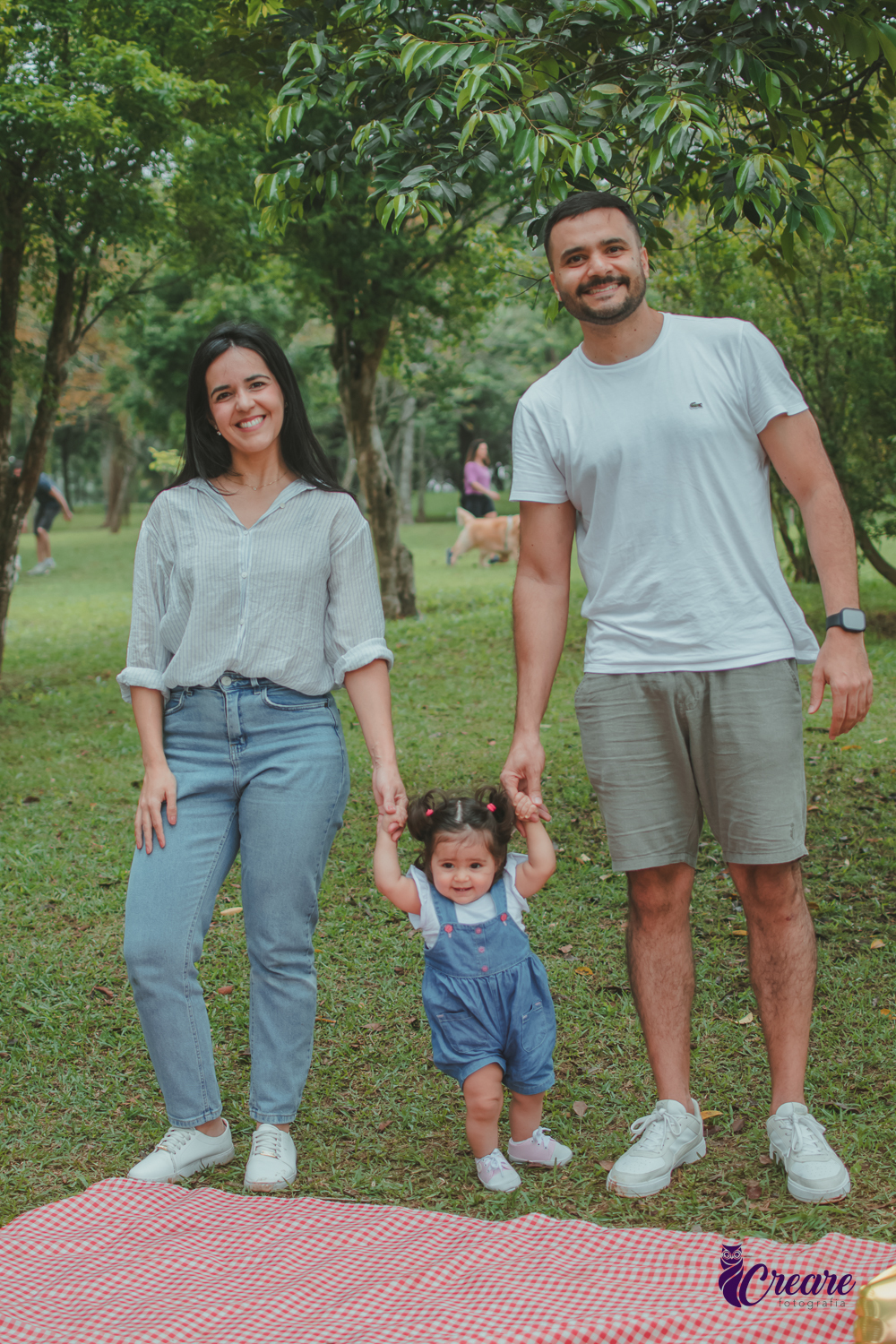 Um casal de mão dadas com uma bebê, durante festa de aniversário de 1 ano no Parque Central de Santo André.