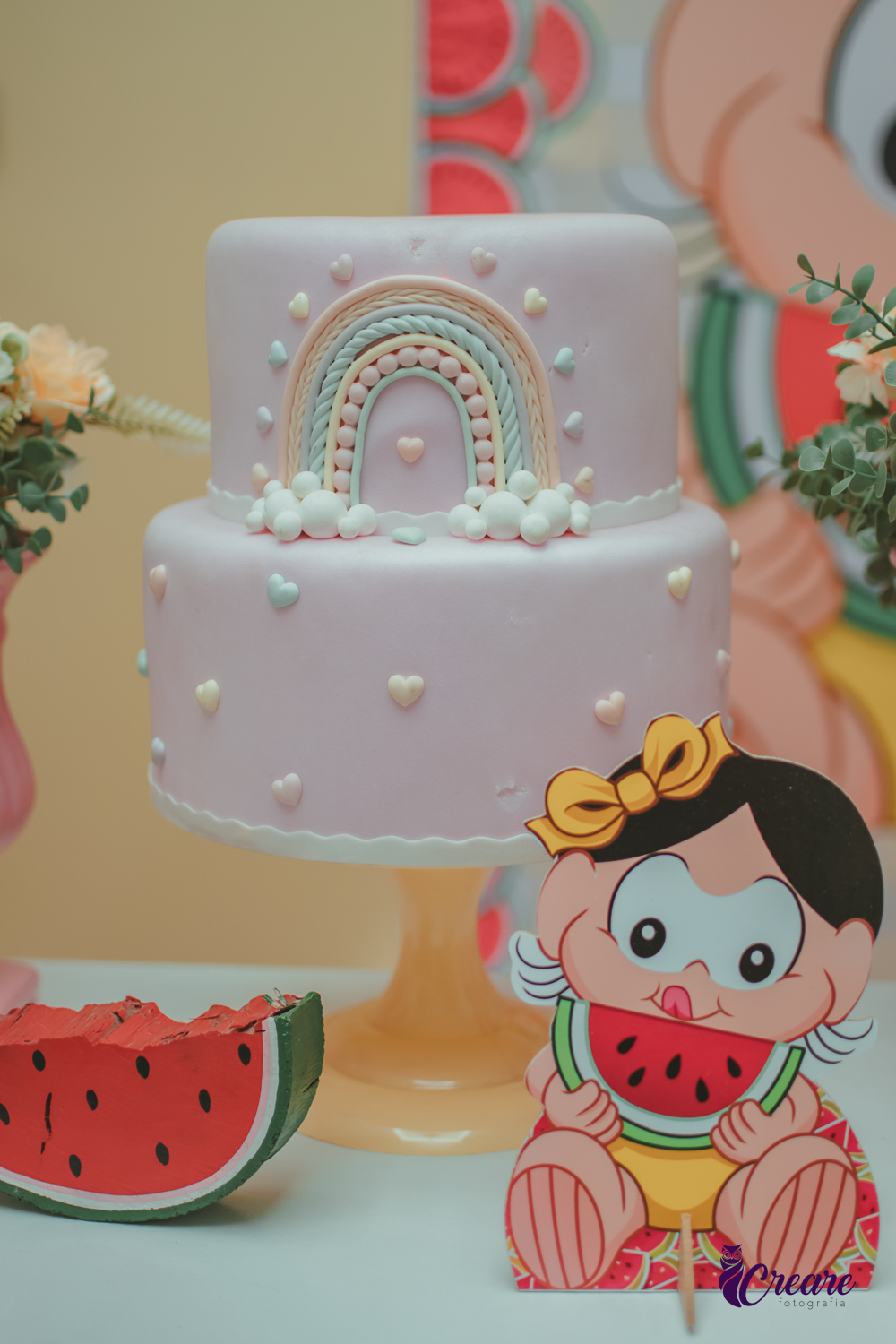 Bolo de aniversário em frente uma magali de madeira.