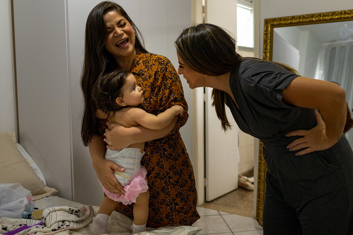 Aniversário Infantil, Rio de Janeiro, Fotografia documental de família, mãe arrumando a filha e madrinha brincando com a afilhada