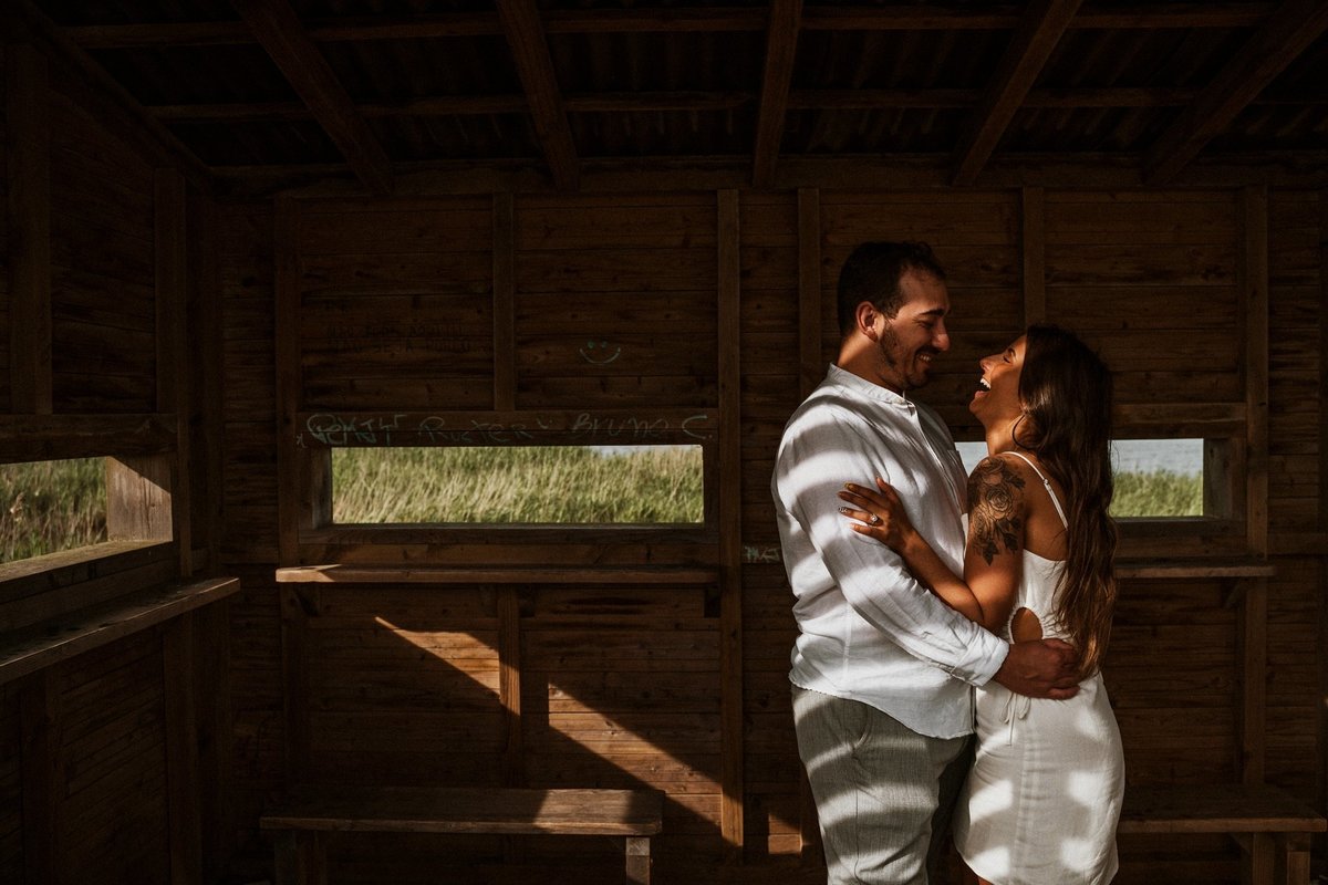 casal abraçado em jogo de luz e sombra, dentro de uma cabana