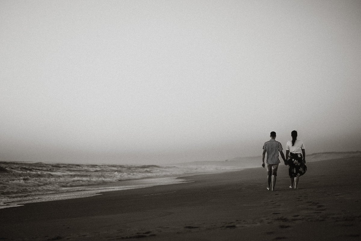 sessão de solteiros Vanessa e do Tiago na praia da torreira ao pôr-do-sol, noivos a caminhar na praia a preto e branco