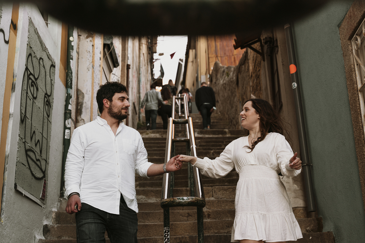 Sessão de solteiros da Sílvia e do Bernardo nas escadarias das ruas  do Porto nas Fontaínhas com luz dramática, casal a caminhas no corrimão.