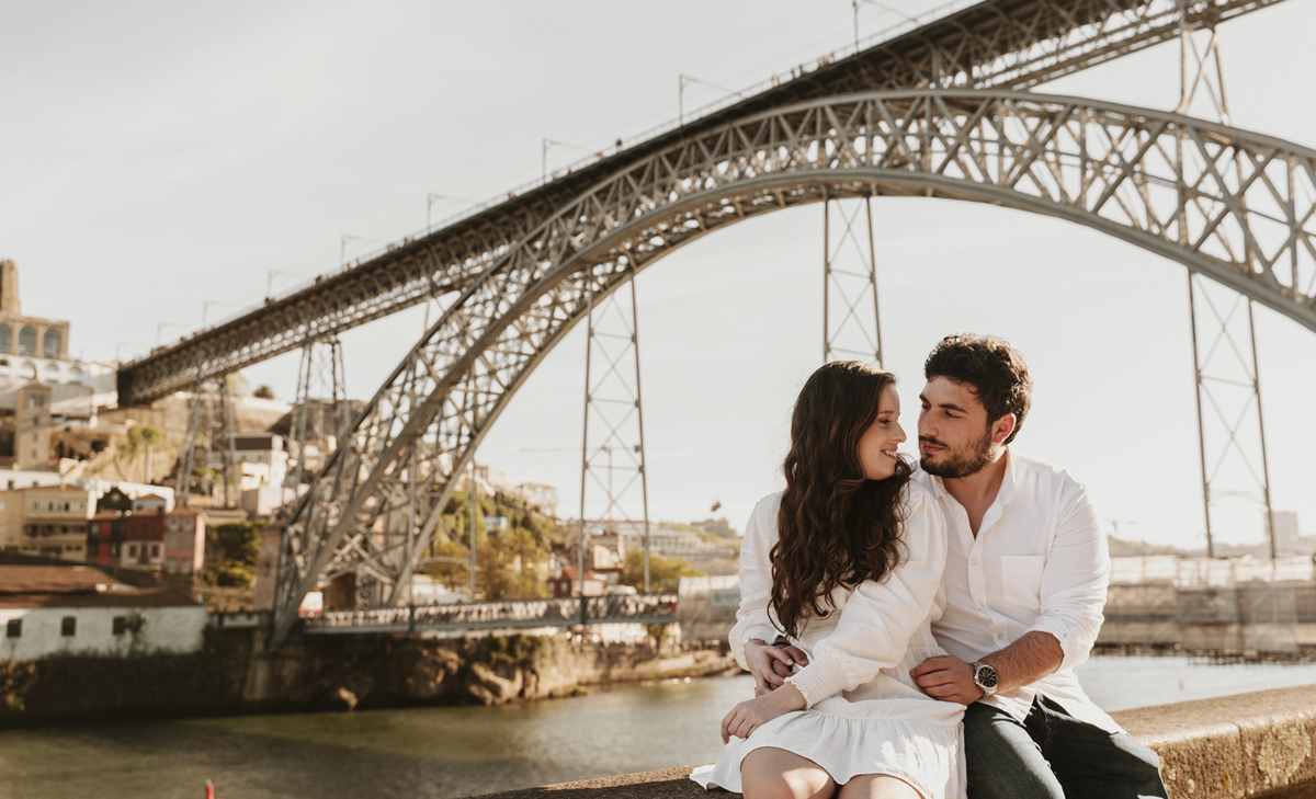 Sessão de solteiros da Sílvia e do Bernardo nas ruas  do Porto na ponte Dão Luís, casal sentado abraçado.