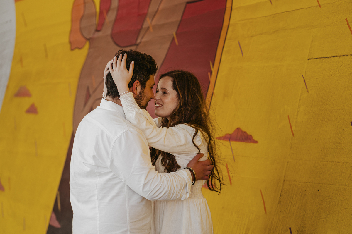 Sessão de solteiros da Sílvia e do Bernardo nas ruas  do Porto na Boavista, com fundo de grafiti amarelo e vermelho e reflexos de prisma óptico.