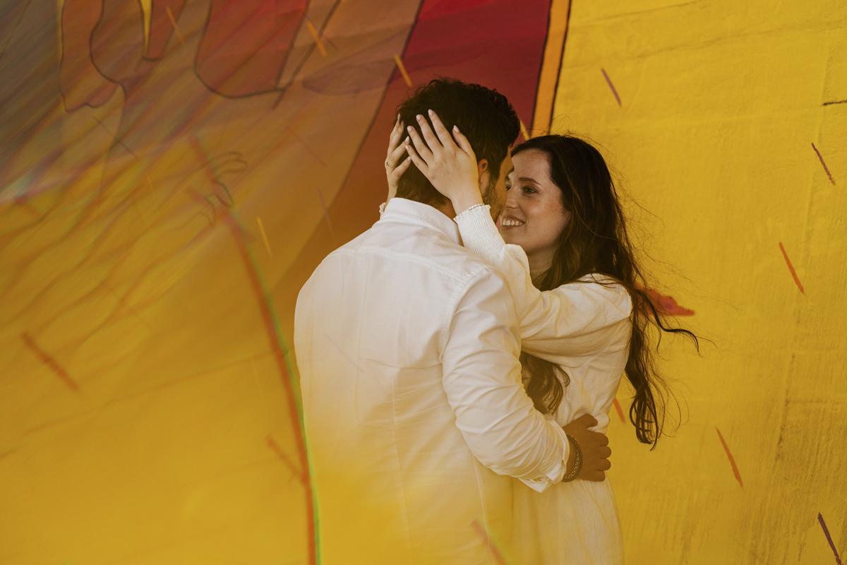 Sessão de solteiros da Sílvia e do Bernardo nas ruas  do Porto na Boavista, com fundo de grafiti amarelo e vermelho e reflexos de prisma óptico.