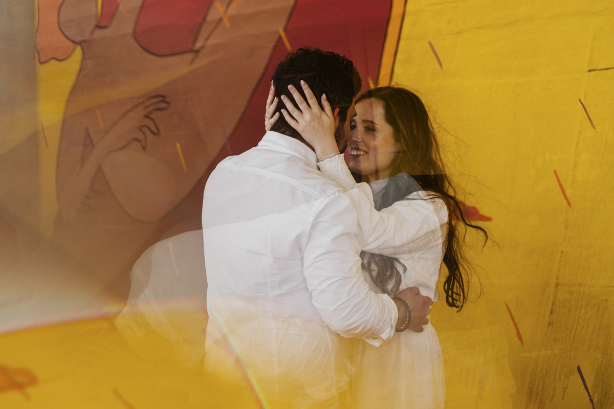 Sessão de solteiros da Sílvia e do Bernardo nas ruas  do Porto na Boavista, com fundo de grafiti amarelo e vermelho e reflexos de prisma óptico.