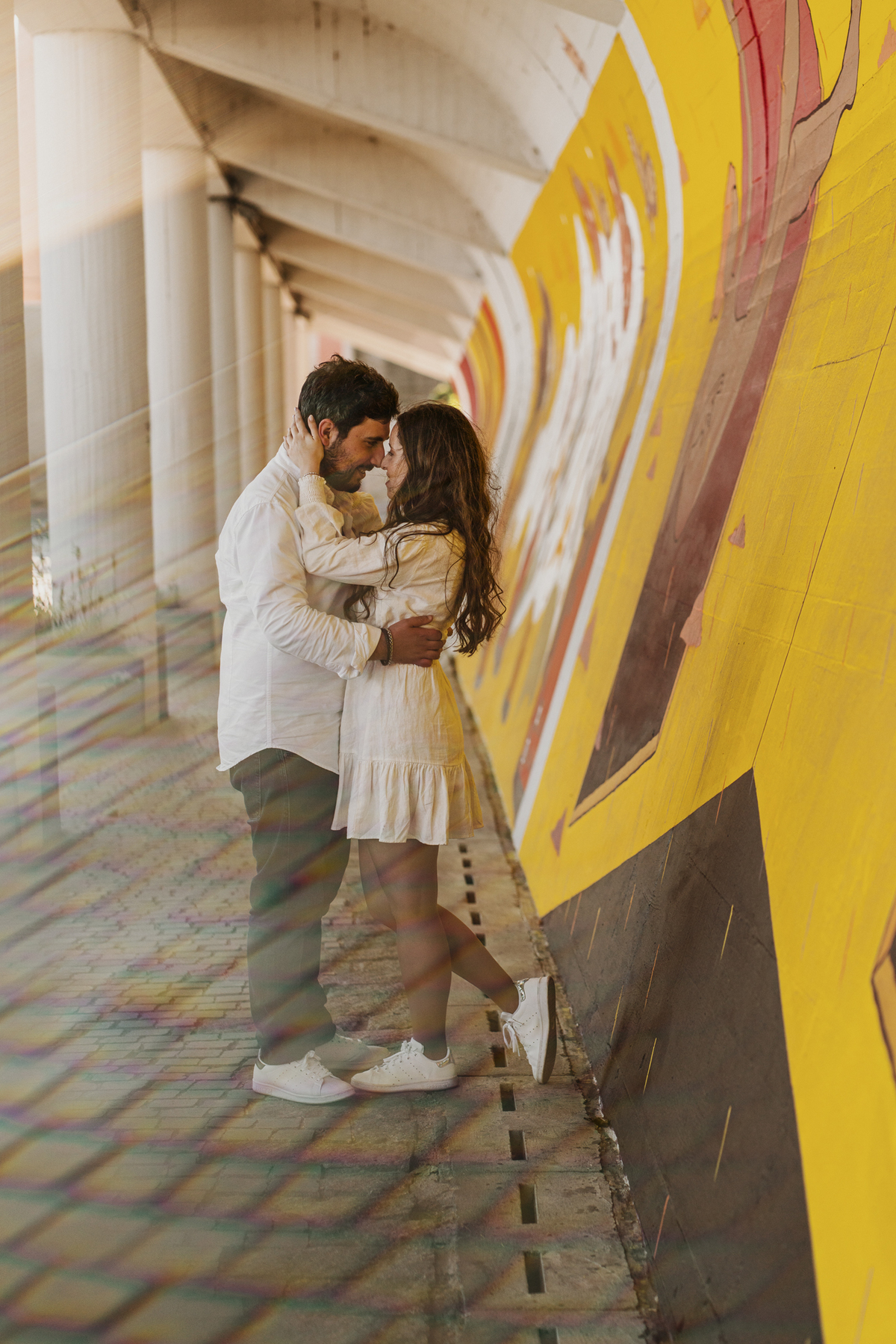 Sessão de solteiros da Sílvia e do Bernardo nas ruas  do Porto na Boavista, com fundo de grafiti amarelo e vermelho e reflexos de prisma óptico.