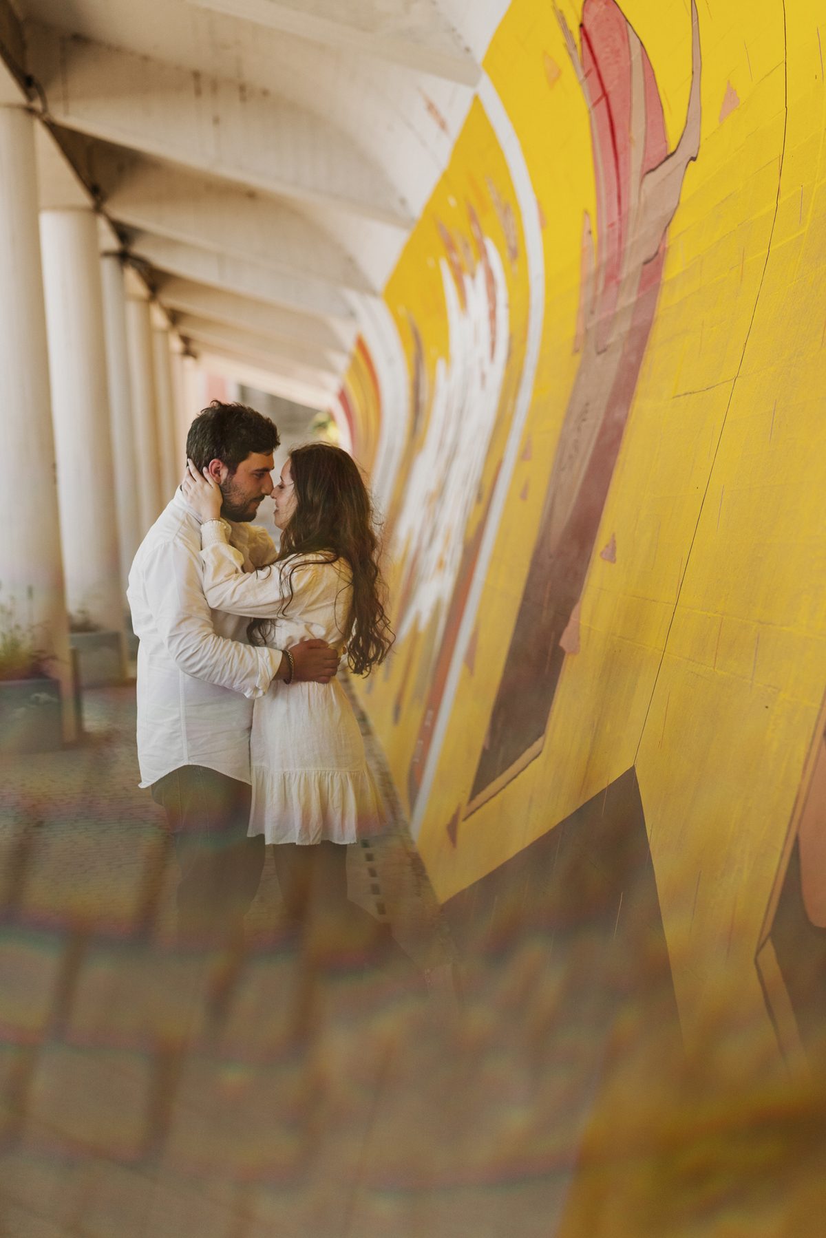 Sessão de solteiros da Sílvia e do Bernardo nas ruas  do Porto na Boavista, com fundo de grafiti amarelo e vermelho e reflexos de prisma óptico.