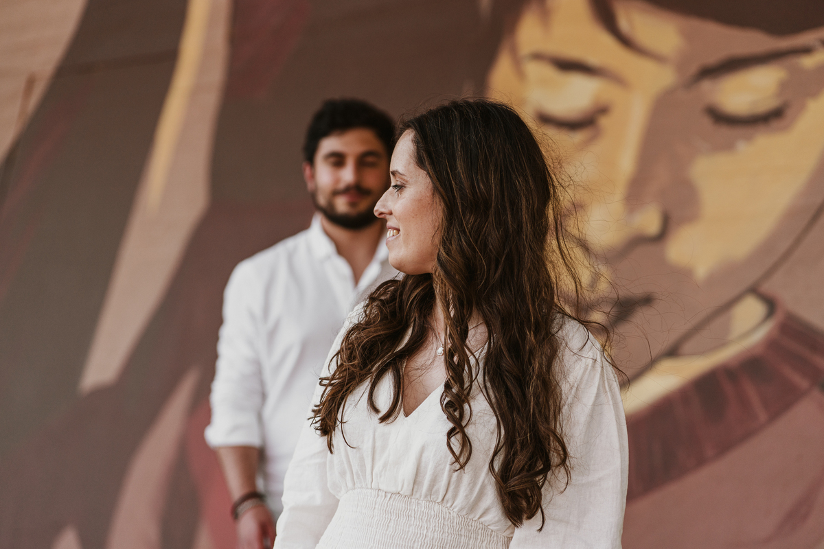 Sessão de solteiros da Sílvia e do Bernardo nas ruas  do Porto na Boavista, com fundo de grafiti amarelo e vermelho e reflexos de prisma óptico.