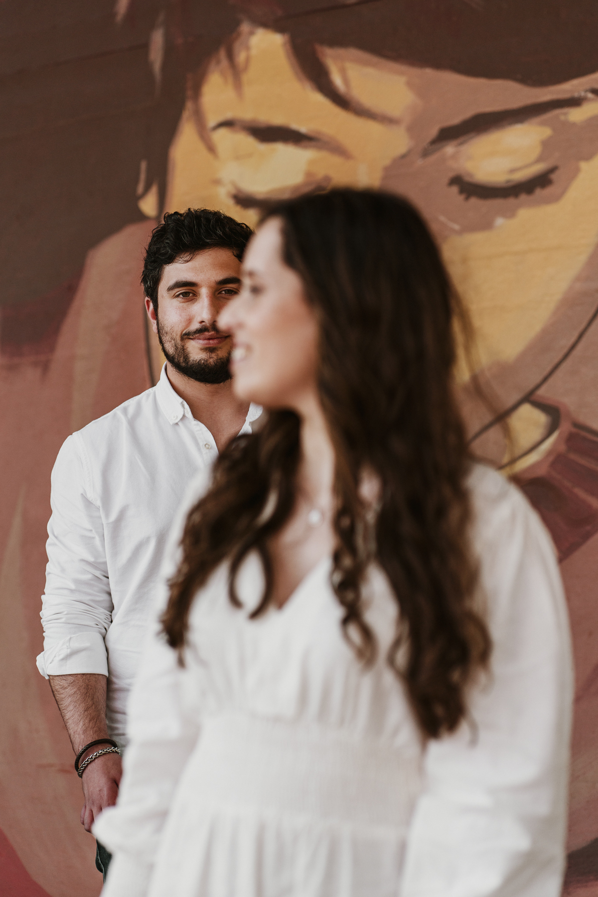 Sessão de solteiros da Sílvia e do Bernardo nas ruas  do Porto na Boavista, com fundo de grafiti amarelo e vermelho e reflexos de prisma óptico.