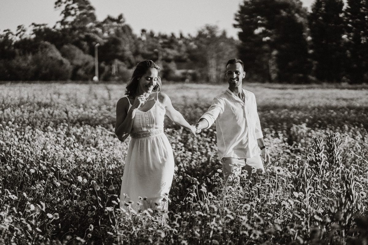 Joana e Tiago, noivos agarrados ao pôr-do-sol num campo de flores amarelas, noivos nos malmequeres, noivos nos girassóis, preto e branco.