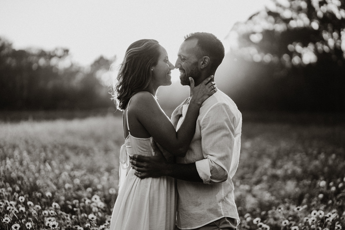 Joana e Tiago, noivos agarrados ao pôr-do-sol num campo de flores amarelas, noivos nos malmequeres, noivos nos girassóis, preto e branco