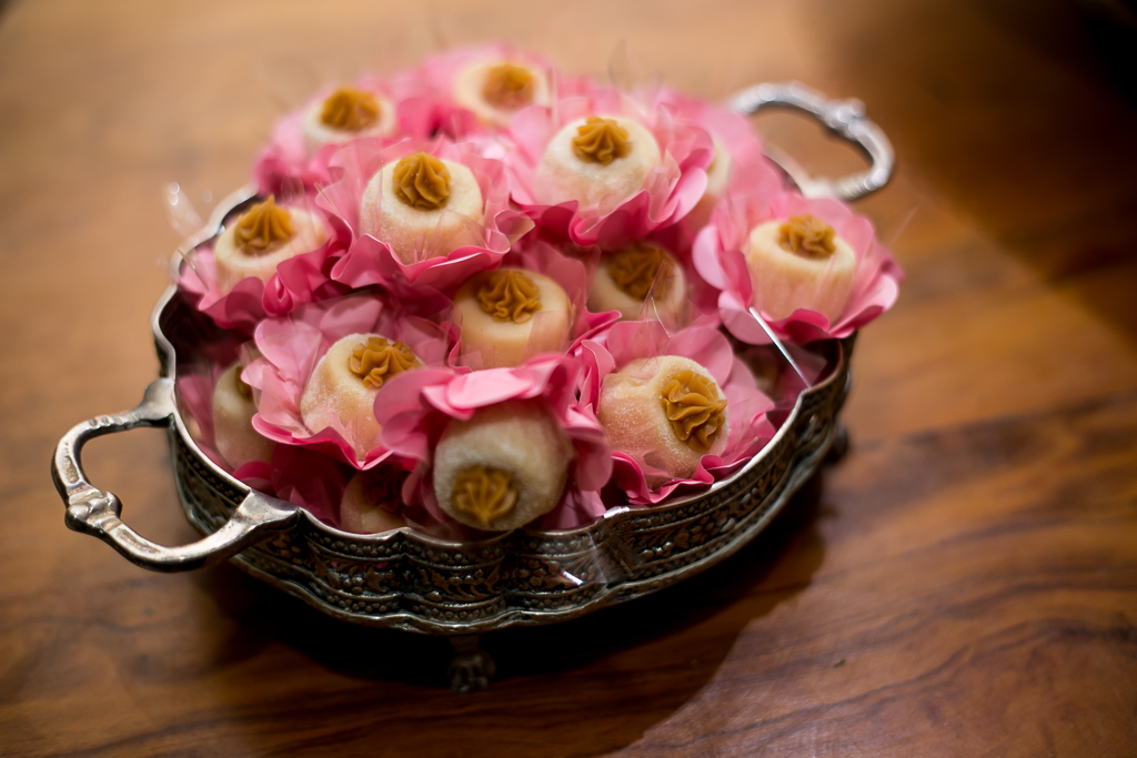 Doces de casamentos em forminhas de flor rosa dentro de bandeja de ferro em cima de mesa de madeira rústica em fotografia de Mariana Seelinger Fotógrafa de Casamentos em Niterói e RJ