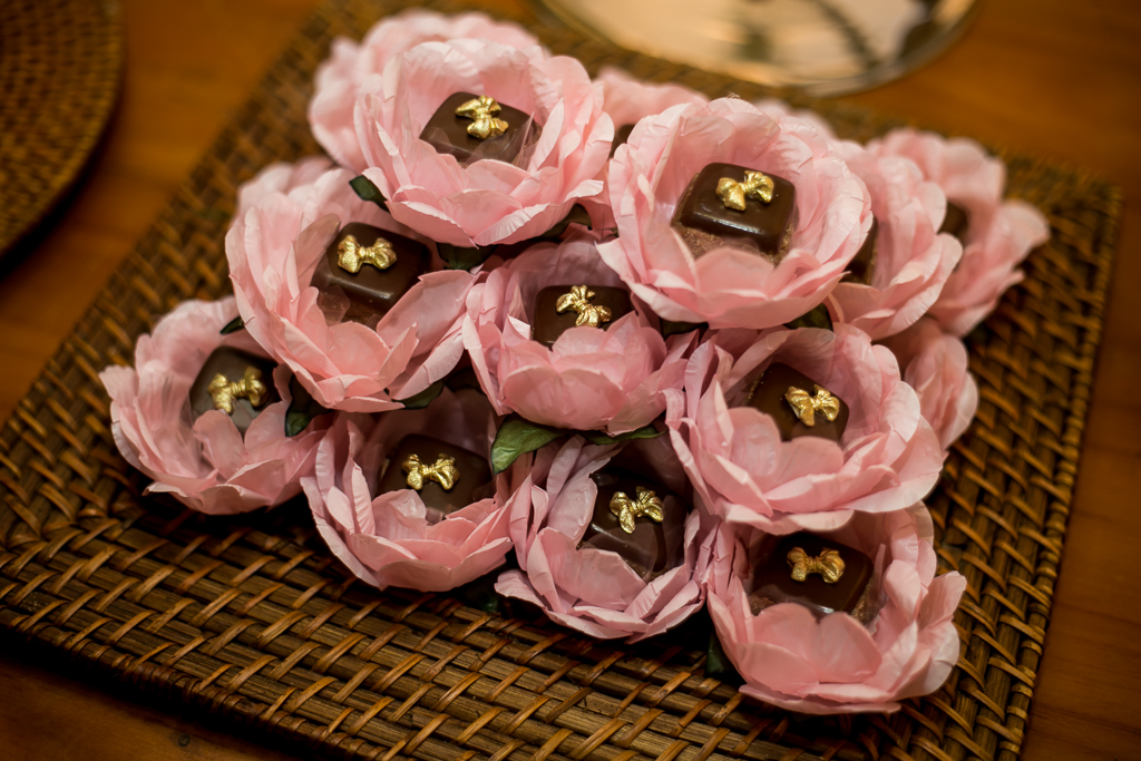 Foto de doces de chocolate com forminhas de flores rosas dentro de uma bandeja de palha em fotografia de Mariana Seelinger Fotógrafa de Casamentos em Niterói e RJ