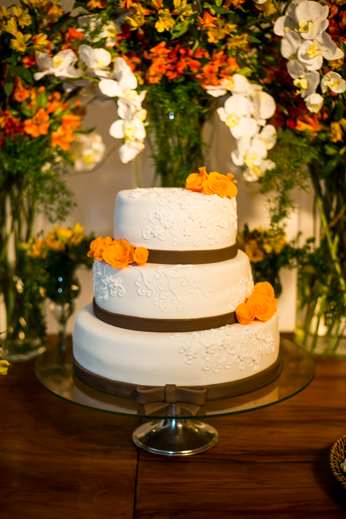 Fotografia do bolo de casamento com três andares com faixas marrons e flores laranjas em fotografia de Mariana Seelinger Fotógrafa de Casamentos em Niterói e RJ