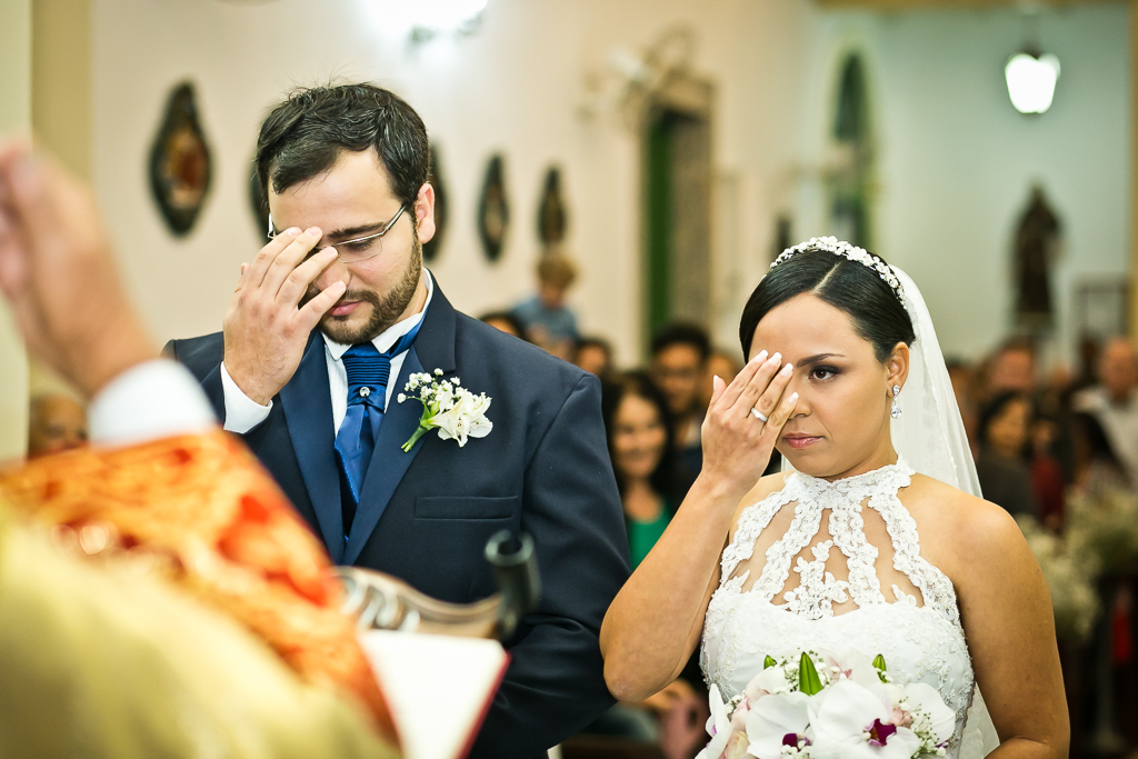 Noivo e noiva fazendo o sinal da cruz durante seu casamento em fotografia de Mariana Seelinger Fotógrafa de Casamentos em Niterói e RJ