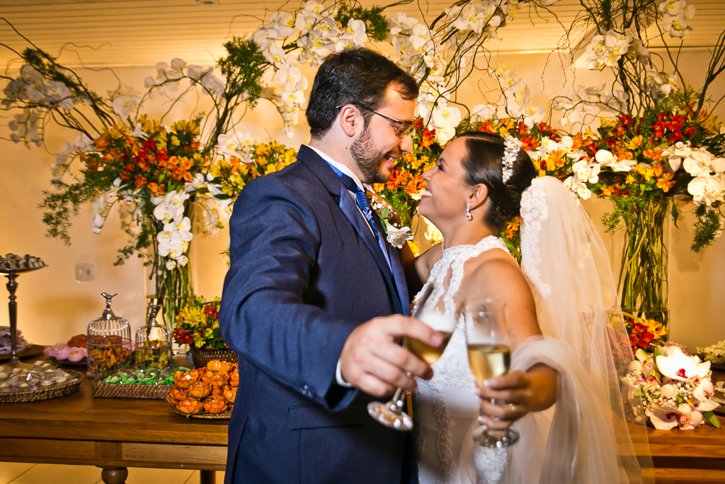 Casal de noivos brindando na mesa do bolo em fotografia de Mariana Seelinger Fotógrafa de Casamentos em Niterói e RJ