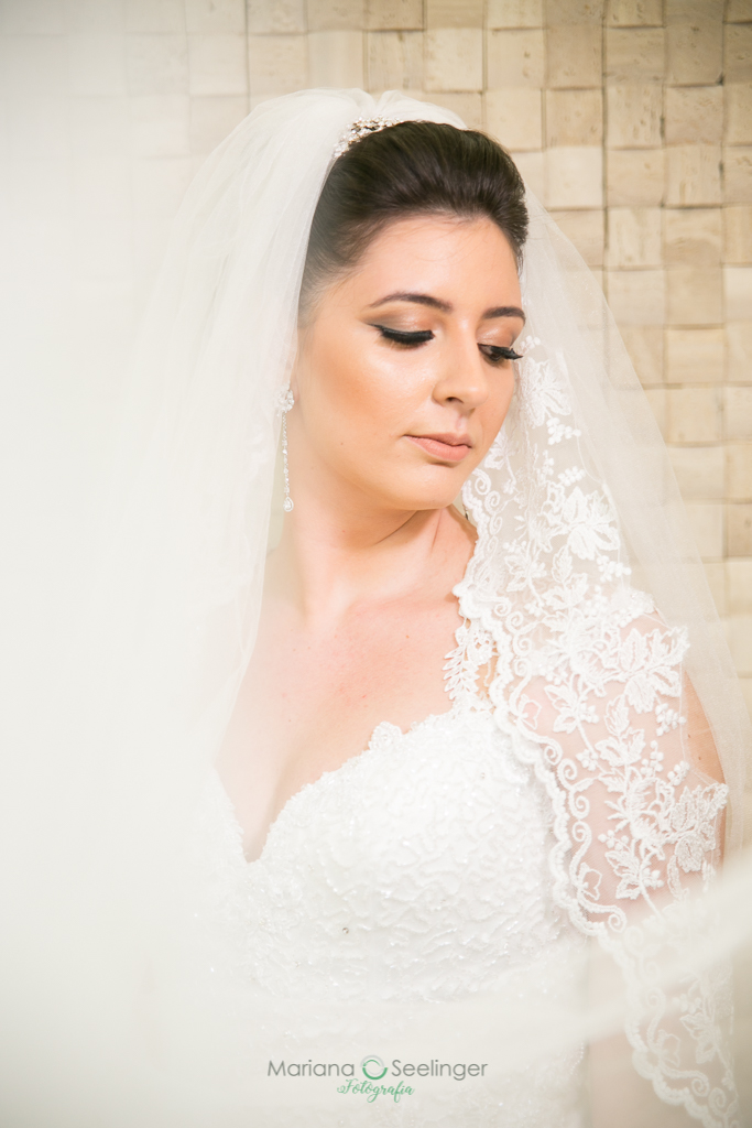 rosto da noiva em destaque a frente da parede de pedras claras durante o making of da noiva em fotografia de Mariana Seelinger fotógrafa de casamentos e famílias em Niterói RJ