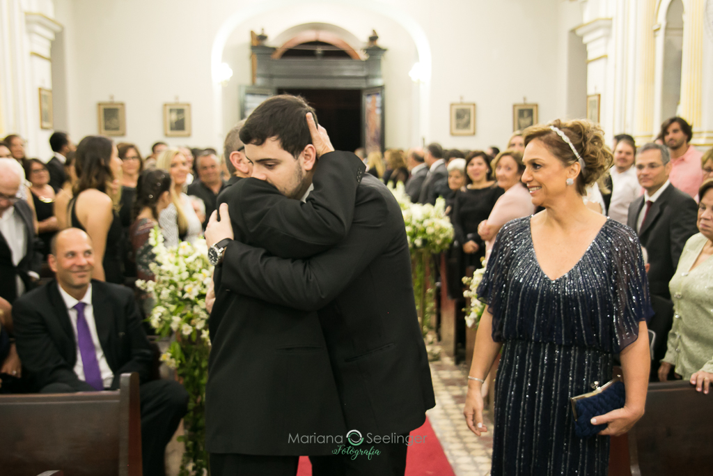 Noivo abraçando seu pai no altar em fotografia de Mariana Seelinger Fotógrafa de Casamentos em Niterói e RJ