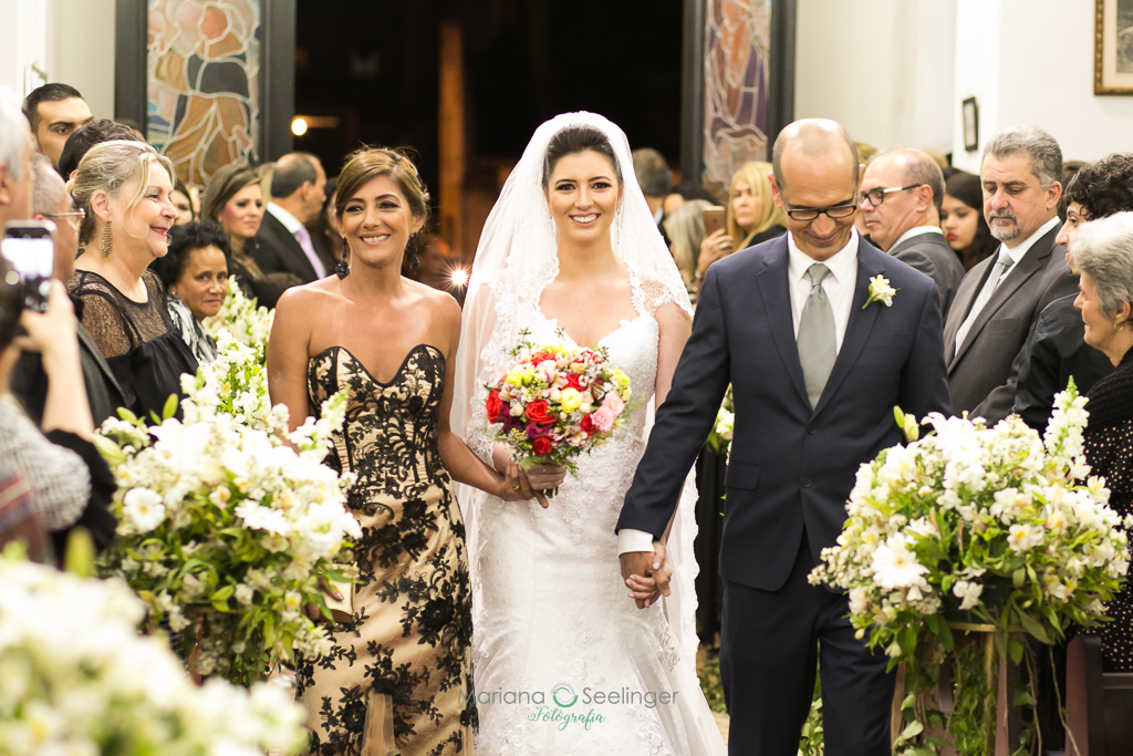 noiva entrando na igreja com seus pais em fotografia de Mariana Seelinger fotógrafa de casamentos e famílias em Niterói RJ