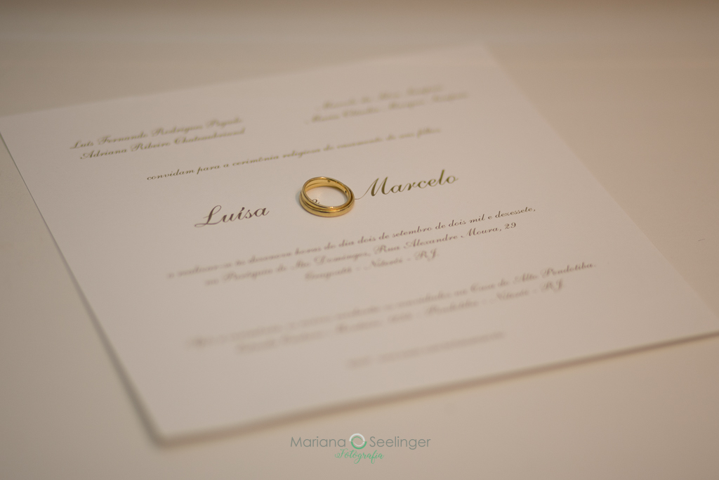 convite de casamento sob alianças em ouro em fotografia de Mariana Seelinger fotógrafa de casamentos e famílias em Niterói RJ