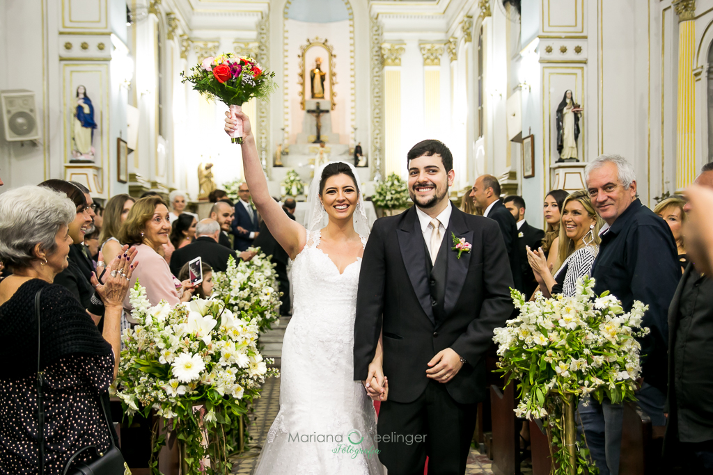 Noivo e noiva saindo do altar a caminho da festa em fotografia de Mariana Seelinger Fotógrafa de Casamentos em Niterói e RJ