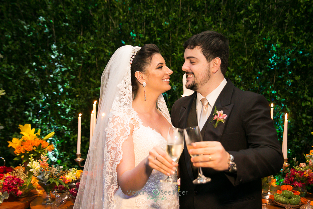 Noivo e noiva brindando no local da festa ddo casamento em fotografia de Mariana Seelinger Fotógrafa de Casamentos em Niterói e RJ