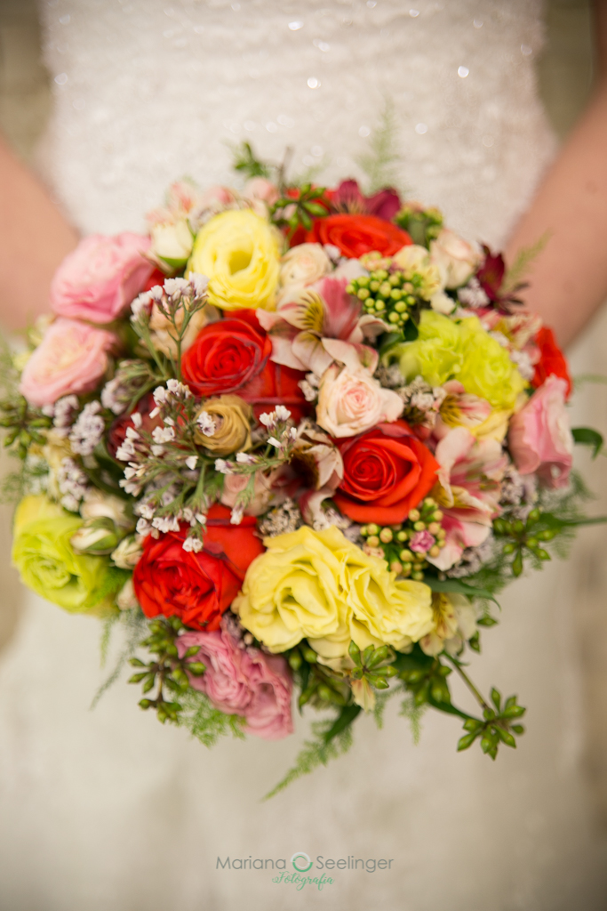 bouquet de flores coloridas com noiva em fundo desfocado em fotografia de Mariana Seelinger fotógrafa de casamentos e famílias em Niterói RJ