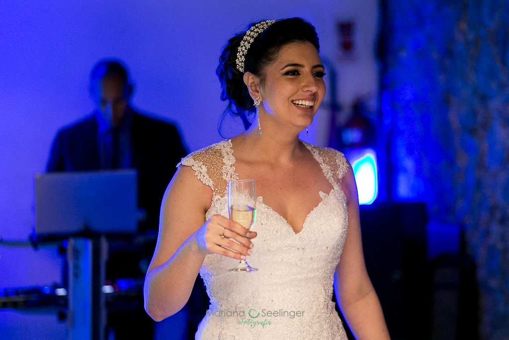 Noiva em sua festa de casamento com taça na mão em fotografia de Mariana Seelinger Fotógrafa de Casamentos em Niterói e RJ
