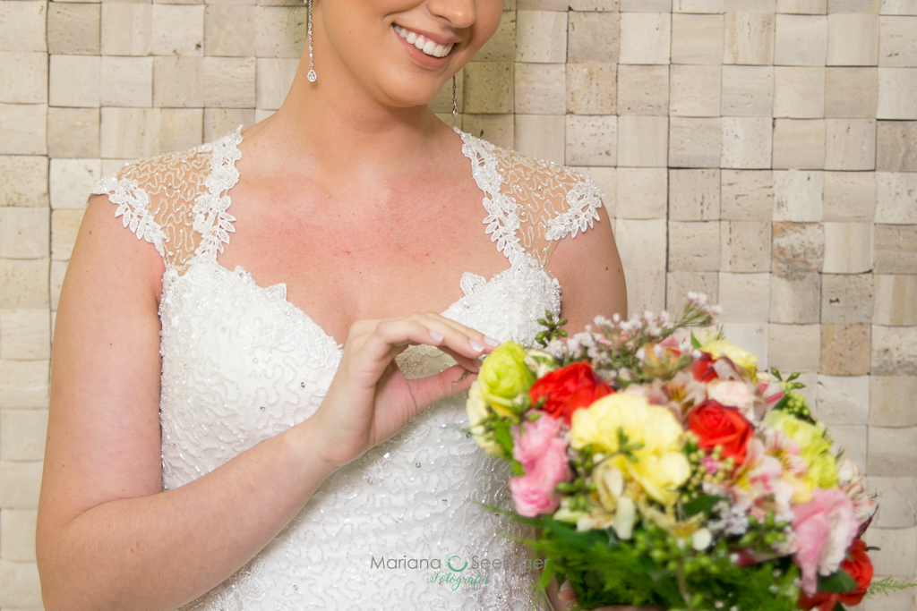 noiva olhando ao bouquet de flores coloridas e vestido de renda vazada emdecotecoração em fotografia de Mariana Seelinger fotógrafa de casamentos e famílias em Niterói RJ