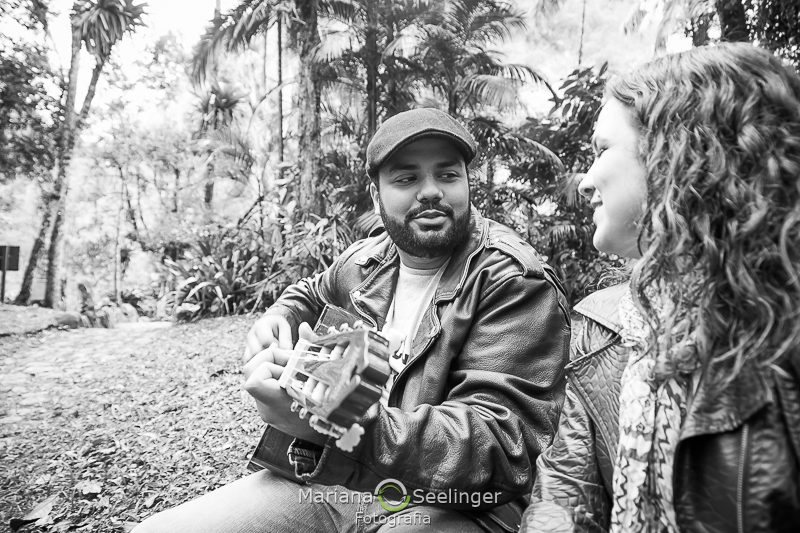 Caio tocando violão ao lado de Ju que assiste apaixonada em clique por Mariana Seelinger Fotografia