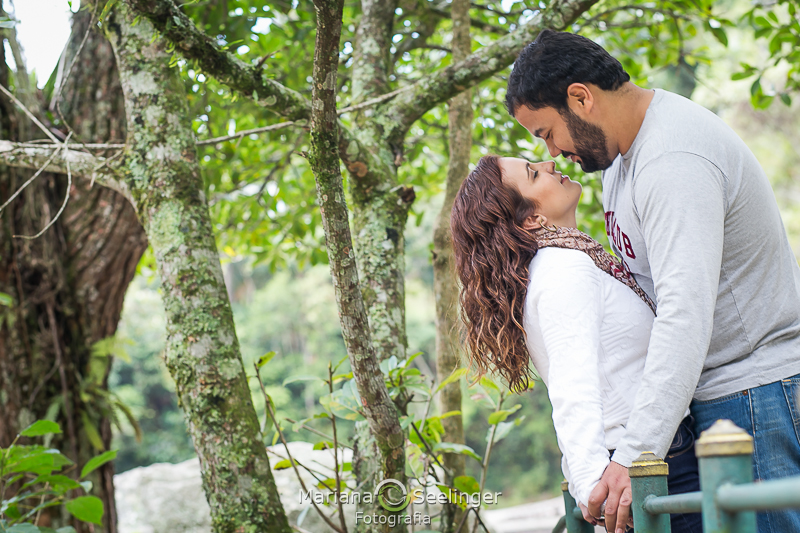 Ju e Caio se observam de perto num quase abraço ao lado de uma árvore
