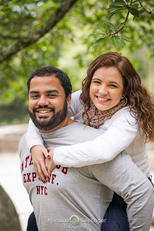 Close dos noivos sorridentes ela pendurada em suas costas em seu ensaio de casal por Mariana Seelinger Fotografia
