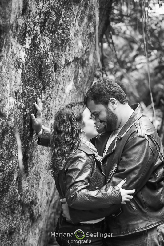 Fotografia em preto e branco do casal abraçado contra uma pedra em Teresópolis - RJ por Mariana Seelinger Fotografia