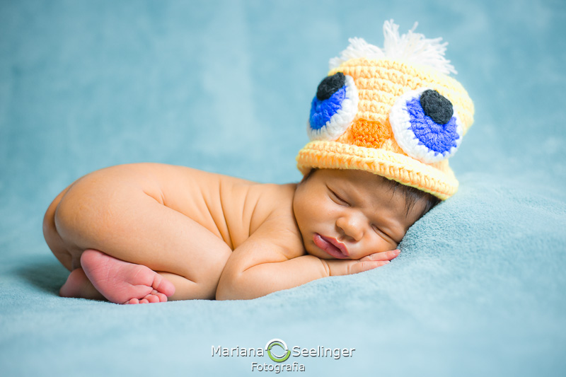 Chapéuzinho de crochê de pato deitado em cobertor azul em Maricá - RJ por Mariana Seelinger