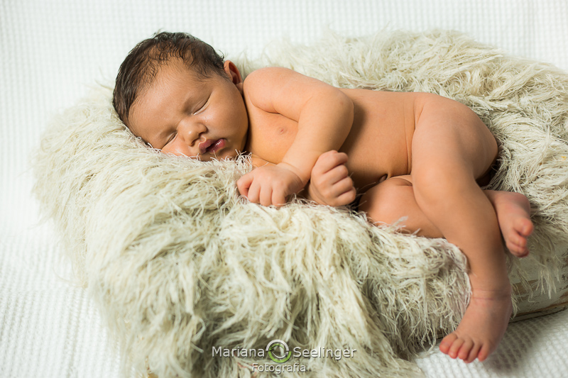 Deitado num tapete creme felpudo em ensaio recém nascido por Mariana Seelinger Fotografia