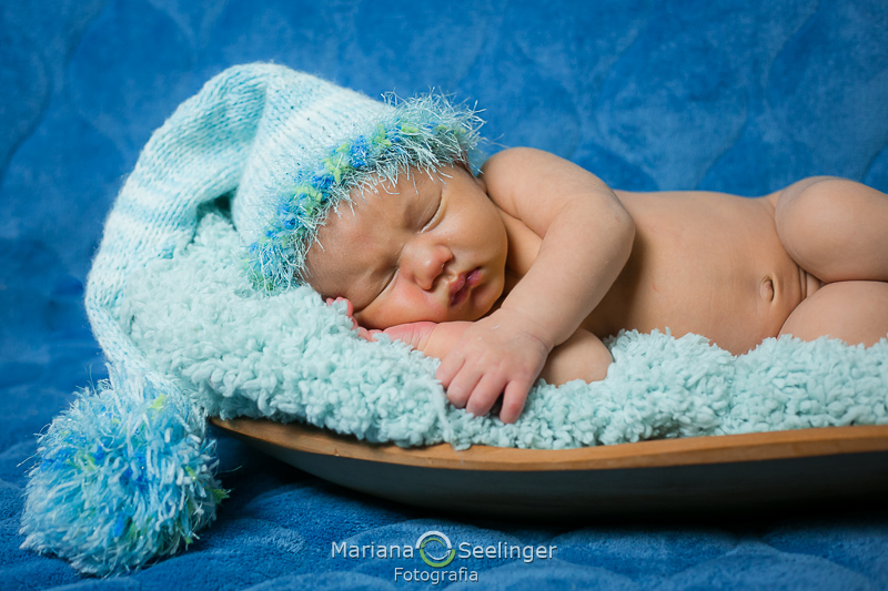 deitado no barquinho com mantinha e touquinha azul em ensaio recém nascido em Niterói por Mariana Seelinger Fotografia