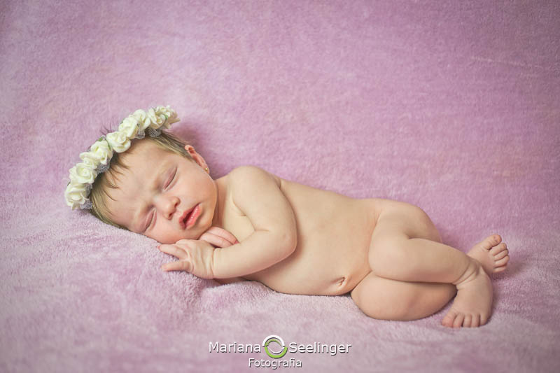 em manta rosa a bebê Maria Antonia deitada de lado em ensaio newborn por Mariana Seelinger Fotografia