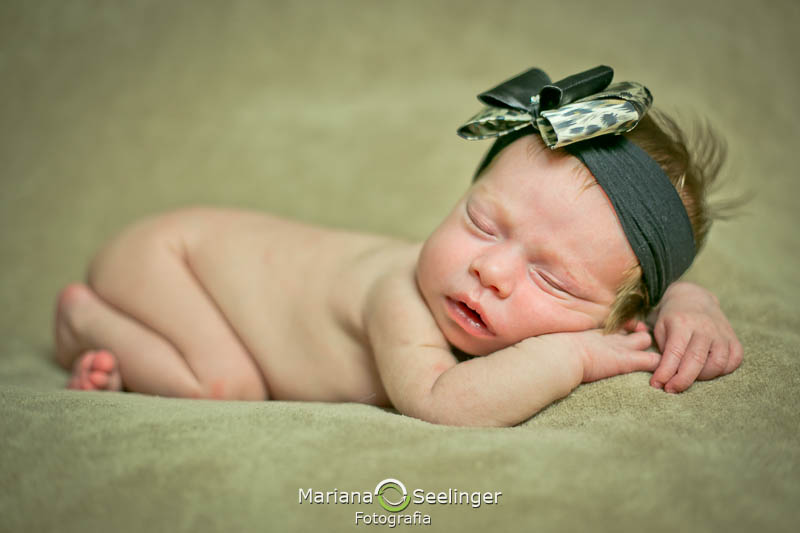 Com tiara verde e branca de bolinhas a recém nascida Maria Antonia dorme em seu ensaio newborn em Niterói - RJ