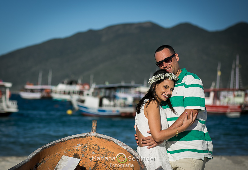 Vanessa e Felipe se abraçam ao lado do barco com o mar ao fundo em ensaio por Mariana Seelinger Fotografia em Arraial do Cabo - RJ